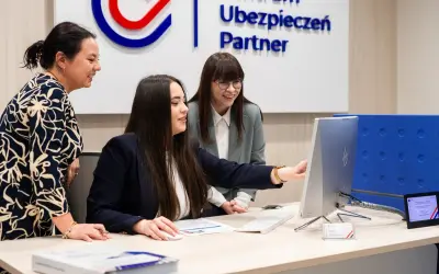 Trzy kobiety przy biurku analizują dane na komputerze.