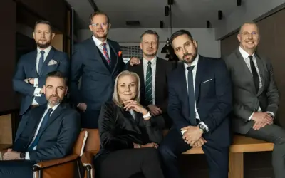 Grupa siedmiu profesjonalistów w garniturach, w tym jedna kobieta, pozuje do zdjęcia.