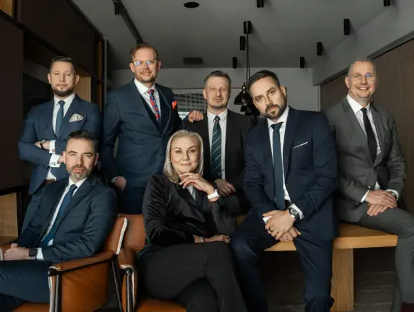 Grupa siedmiu profesjonalistów w garniturach, pozujących do zdjęcia w biurze.